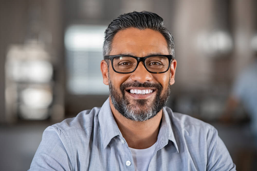 Smiling mature indian man wearing spectacles and looking at camera